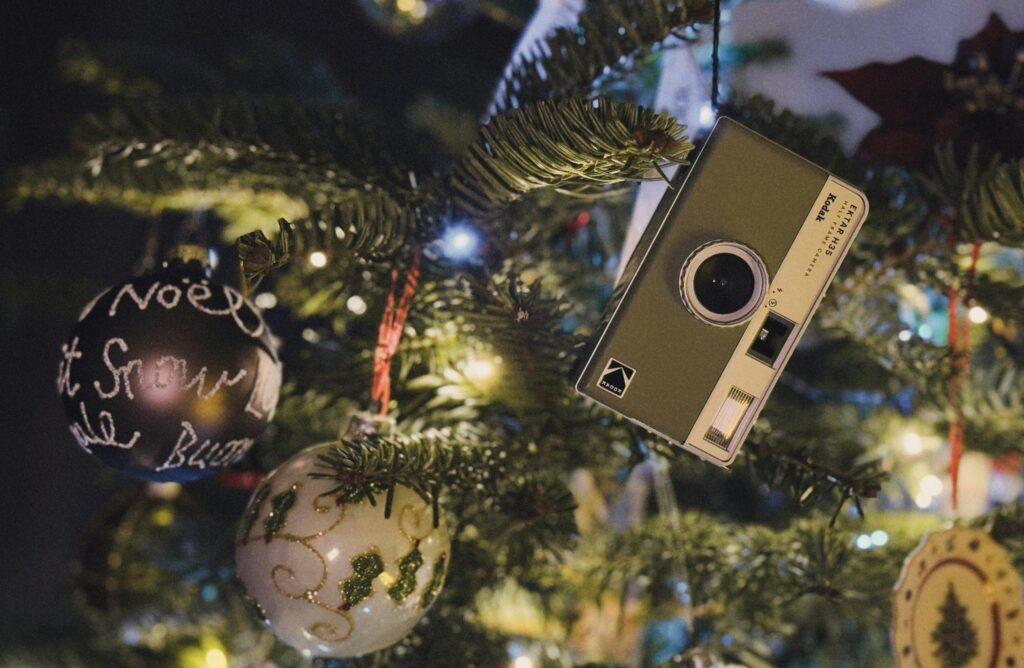 A vintage camera decorates a festive Christmas tree with lights and ornaments.